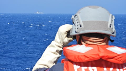 A crewman onboard the Taiwanese Navy vessel Kunming looks out at Chinese warship Yinchuan