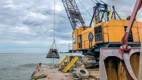 Dredging equipment and a crane barge at Sandusky Harbor, Ohio, with the shoreline and Lake Erie in the background.