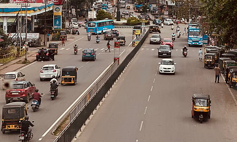 Photo of street view in Thrissur with vehicles, people, under a cloudy sky