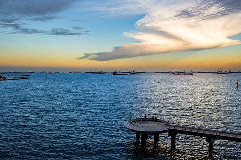 Photo of sunset at Singapore's coastline with ships and a pier overlooking the ocean