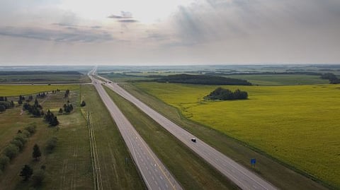 Photo of Sylvan Lake highway with expansive fields under summer sky