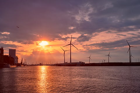 Photo of vessels and wind turbines at Antwerp Port at sunset