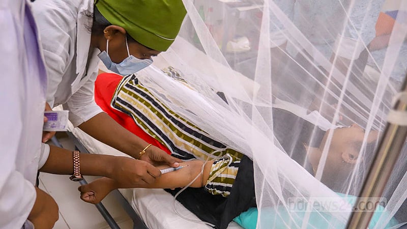 A health worker collects blood sample from a dengue patient at Shaheed Suhrawardy Medical College Hospital.