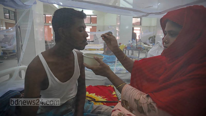 The wife feeds Rabiul Alam, a dengue patient, at Shaheed Suhrawardy Medical College Hospital on Tuesday, Aug 30, 2022.