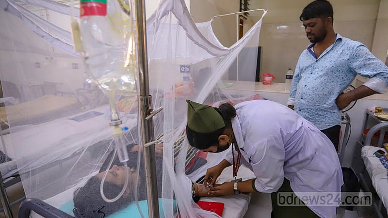A health worker collects blood sample from a dengue patient at Shaheed Suhrawardy Medical College Hospital.