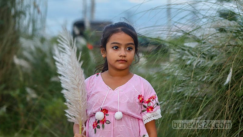 A child grabs plumes of Kans grass in Dhaka's Aftabnagar.