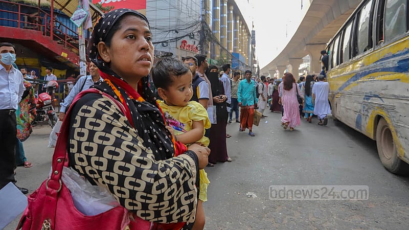 A woman with a child on her lap waits for a bus at Dhaka’s Mirpur-10 on Monday, Oct 17, 2022.