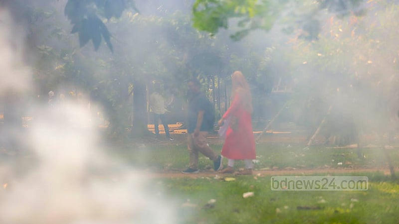 Sightseers walk in smoke from burning waste in Dhaka’s Suhrawardy Udyan on Oct 30, 2022.