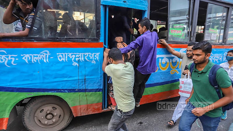 Commuters rush to board a running bus after a long wait in Dhaka’s Mirpur-10 on Monday, Oct 17, 2022.