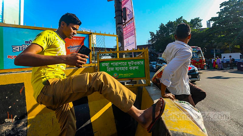 Dhaka Metropolitan Traffic Police’s signpost on top of a road divider in Mohakhali advises pedestrians to use the footbridge located just a few paces away but jaywalkers are ignoring the safety caution on Sunday, Oct 23, 2022.