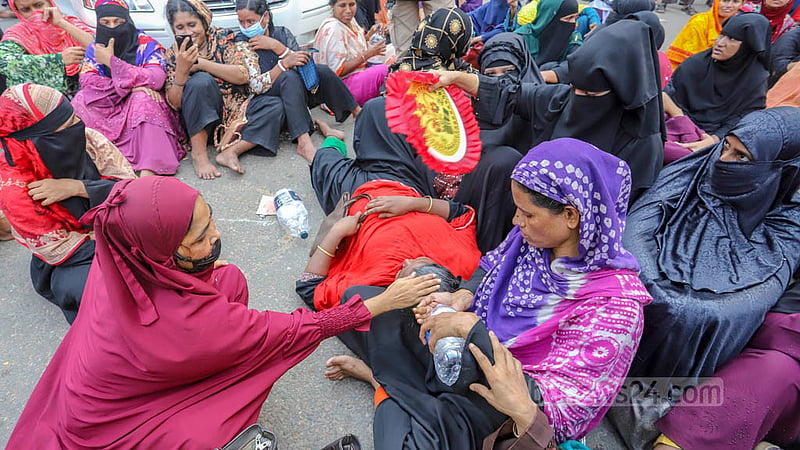 Fellow workers of Olio Apparels Ltd help a woman by pouring water on her head as she falls ill during protests demanding back pay in Dhaka’s Arambagh on Tuesday, Nov 1, 2022. Photo: Asif Mahmud Ove
