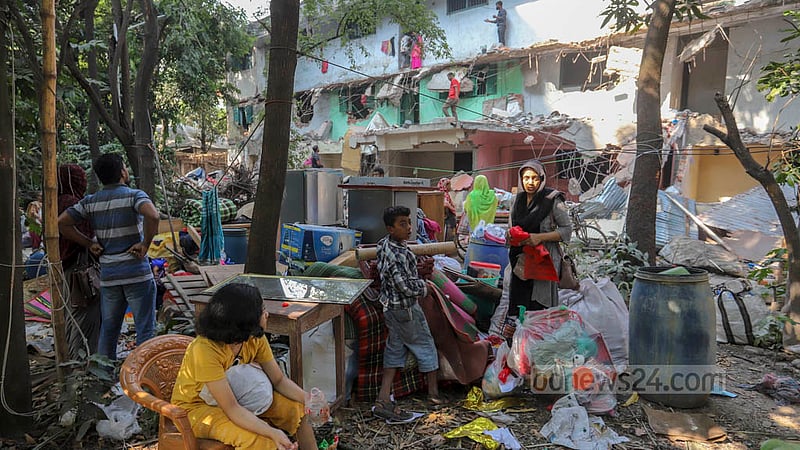 Residents sit outside with their belongings after being evicted from the D-type colony in Dhaka’s Mohammadpur Housing Estate by the National Housing Authority on Wednesday, Nov 23, 2022. They alleged the authority did not give them prior notice. Photo: Asif Mahmud Ove