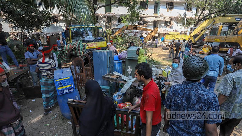 Residents sit outside with their belongings after being evicted from the D-type colony in Dhaka’s Mohammadpur Housing Estate by the National Housing Authority on Wednesday, Nov 23, 2022. They alleged the authority did not give them prior notice. Photo: Asif Mahmud Ove