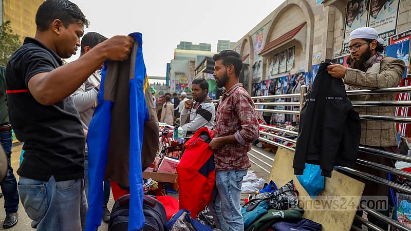 Men check winter jackets at a makeshift shop on the footpath outside New Market in Dhaka.