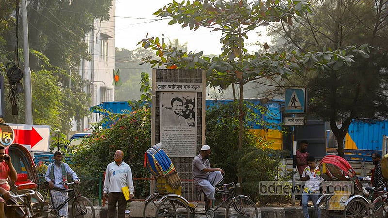 A plaque with the name of the road at the entrance to Mayor Annisul Huq Road at Saat Rasta. Trucks and covered vans are illegally parked behind the plaque. Photo: Mahmud Zaman Ovi