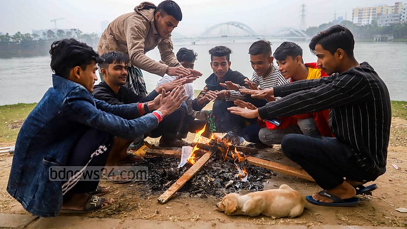Young men sit by a fire next to a footpath in Dhaka’s Hatirjheel for warmth amid cold weather on a winter day. Photo: Mahmud Zaman Ovi