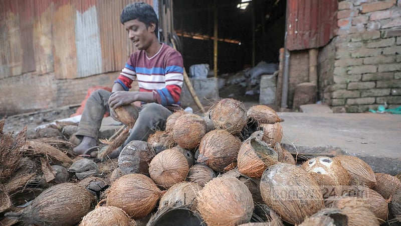 A worker removes husks from coconut shells at a factory producing coconut powder. Photo: Asif Mahmud Ove
