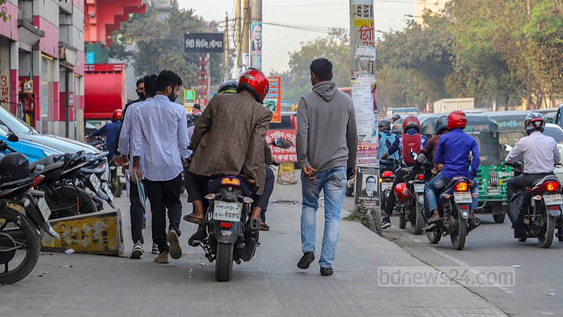 A motorcyclist riskily drives between pockets of spaces between pedestrians on a footpath of Shaheed Tajuddin Ahmed Sarani on Thursday, Feb 2, 2023. Photo: Asif Mahmud Ove