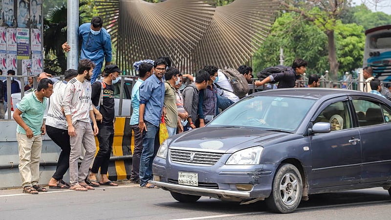 Many candidates cross the busy Airport Road by scaling a traffic median with an underpass next to them in the MES area after bank recruitment tests on Friday, Mar 31, 2023. Photo: Tawhiduzzaman Tapu