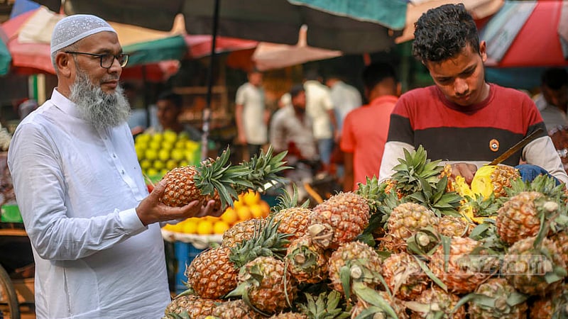 Mohammad Tofayel Ahmed buys pineapples from a rickshaw van in Karwan Bazar for iftar on Thursday, Mar 30, 2023. Photo: Tawhiduzzaman Tapu