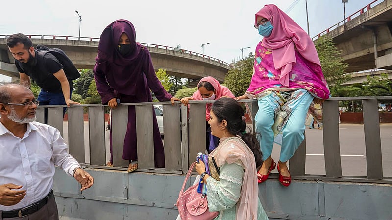 Many female candidates for bank jobs scale a traffic median in the MES area to cross the busy Airport Road in Dhaka after the recruitment tests on Friday, Mar 31, 2023. Photo: Tawhiduzzaman Tapu