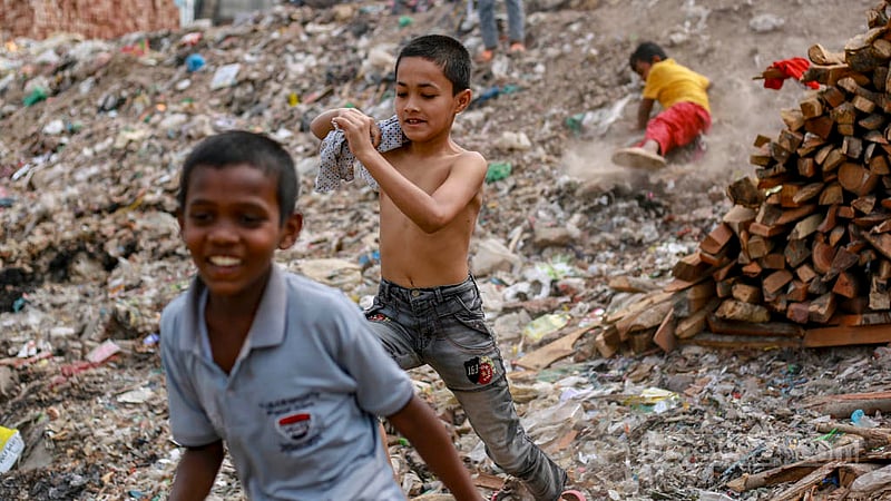 A child falls and slips into the waste while playing at Koyla Ghat waste disposal site in Kamrangirchar on Thursday, Mar 16, 2023. Photo: Tawhiduzzaman Tapu