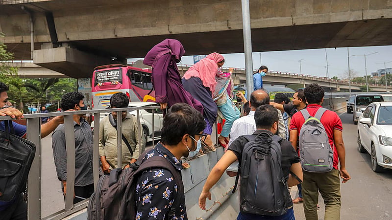 After taking bank recruitment exams, candidates scale a traffic median in the MES area to cross the busy Airport Road in Dhaka on Friday, Mar 31, 2023. Photo: Tawhiduzzaman Tapu