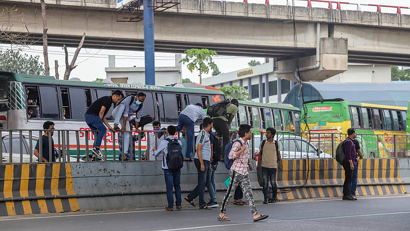 Candidates risk their lives to cross the busy Airport Road by scaling a traffic median in the MES area after bank recruitment exams on Friday, Mar 31, 2023. Photo: Tawhiduzzaman Tapu