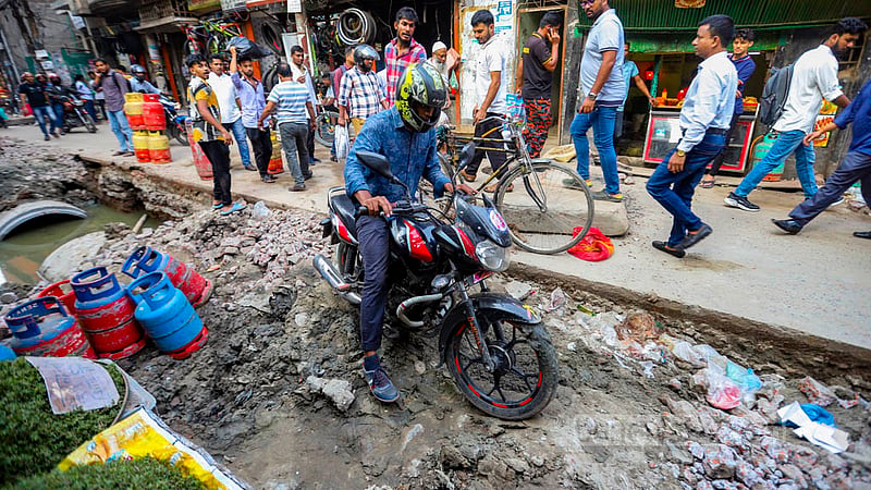 A motorcycle rider navigates the holes dug up on Kazi Alauddin Road in Old Dhaka amid sewage repair works. Photo: Mahmud Zaman Ovi