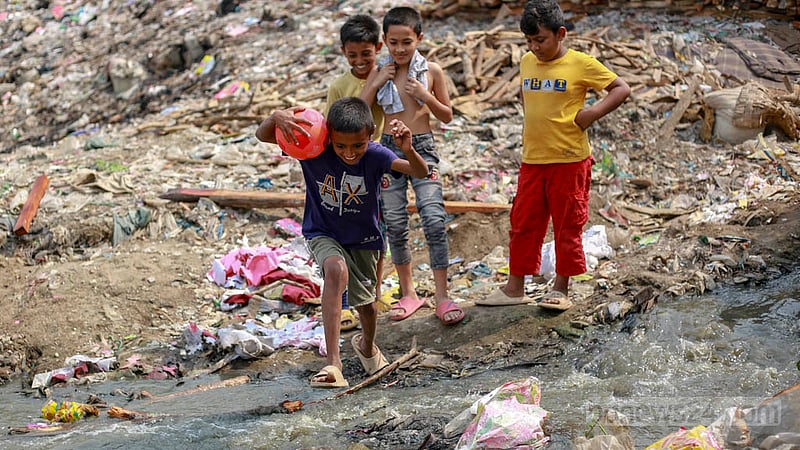 Children cross dirty water in the Koyla Ghat waste disposal site in Kamrangirchar on Thursday, Mar 16, 2023. Photo: Tawhiduzzaman Tapu
