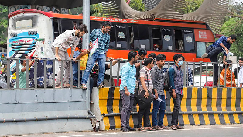 Candidates risk their lives to cross the busy Airport Road by scaling a traffic median in the MES area after bank recruitment exams on Friday, Mar 31, 2023. Photo: Tawhiduzzaman Tapu