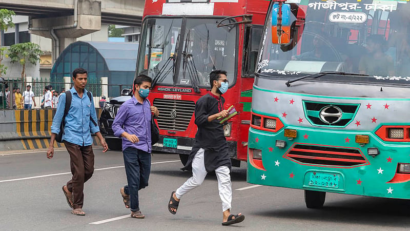 Candidates for bank jobs risk their lives to cross the busy Airport Road by scaling a traffic median with an underpass next to them in the MES area after the recruitment exams on Friday, Mar 31, 2023. Photo: Tawhiduzzaman Tapu