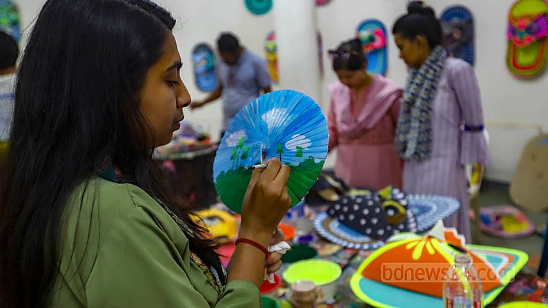 A student of Dhaka University’s Faculty of Fine Arts draws motifs on a paper fan to be sold at their stalls at the entrance of their faculty premises during the Bangla New Year festival. Photo: Mahmud Zaman Ovi