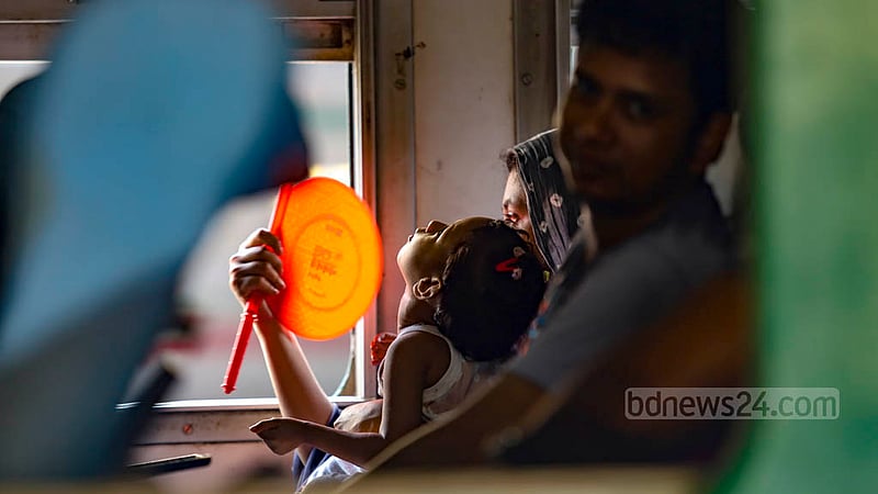 A mother fans her child with a hand fan at a Rajshahi-bound train yet to leave the Kamalapur Railway Station on Tuesday, Apr 18, 2023.