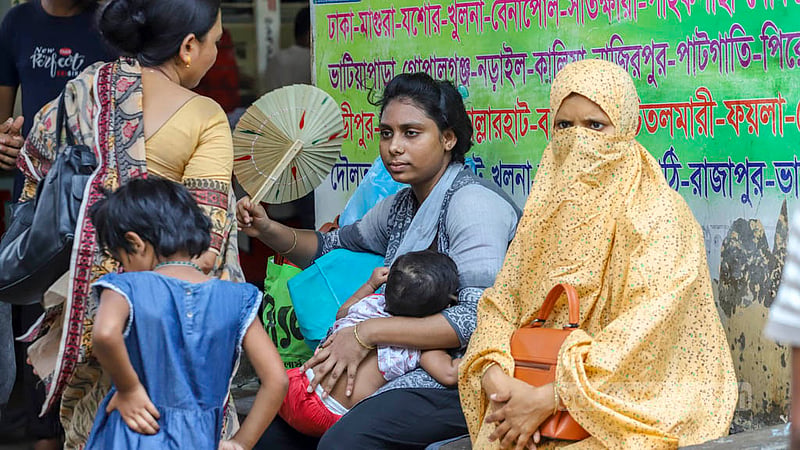 A mother fans her child with a hand fan in the searing heat while waiting for a bus at Gabtoli Bus Terminal to travel back home before Eid-ul-FItr on Tuesday, Apr 18, 2023. Photo: Asif Mahmud Ove