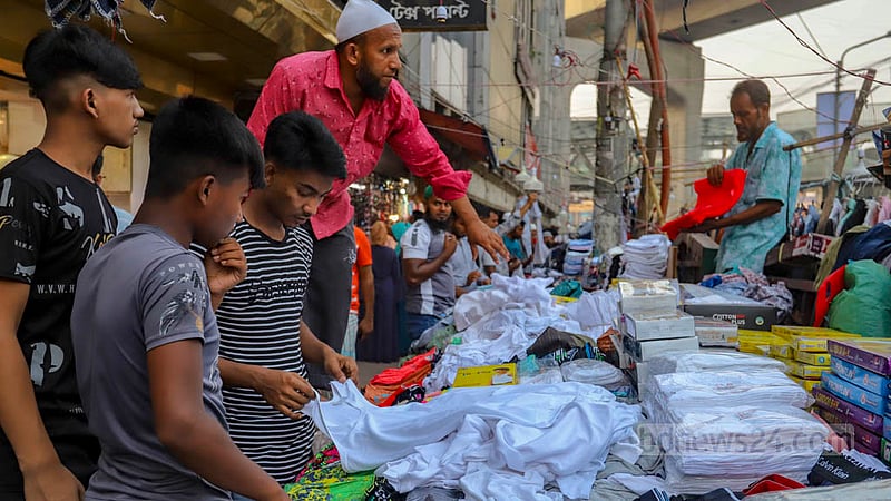 People check shirts at a makeshift shop on the footpath in Dhaka before Eid-ul-Fitr.