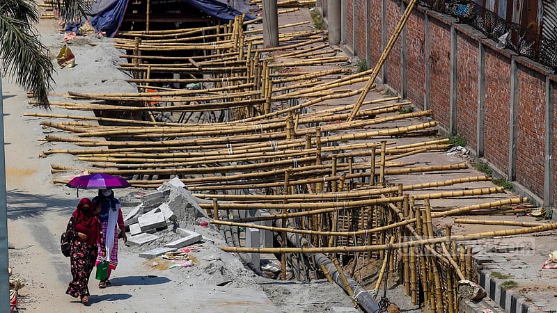 Women walk along a service lane dug up for the installation of underground cables by DPDC on the Rampura-Moghbazar part of Dhaka’s Hatirjheel.
