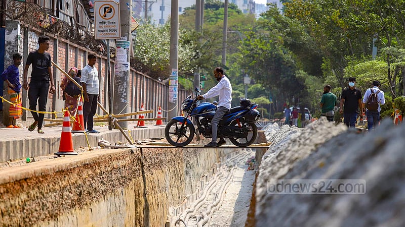 A motorcyclist crosses a hole by using an iron sheet as parts of Hatirjheel Link Road in Dhaka are being dug up for the installation of DPDC cables.