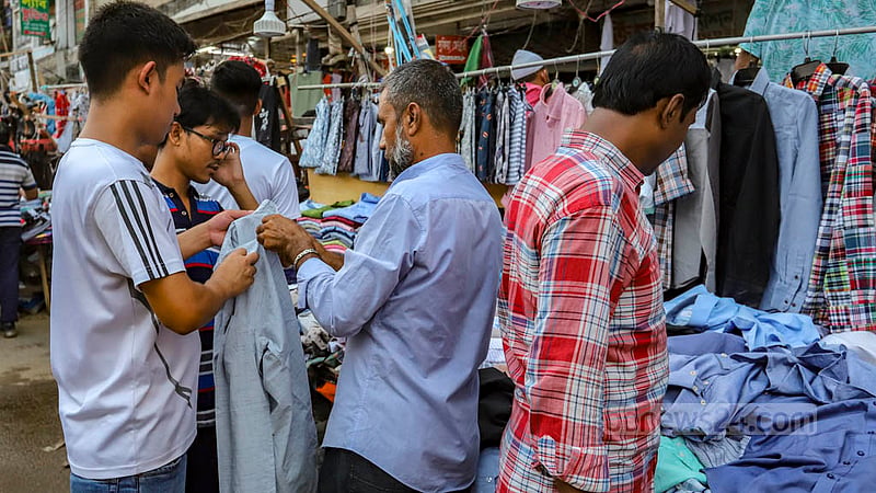 A man checks shirts at a makeshift shop on the footpath in Dhaka before Eid-ul-Fitr.