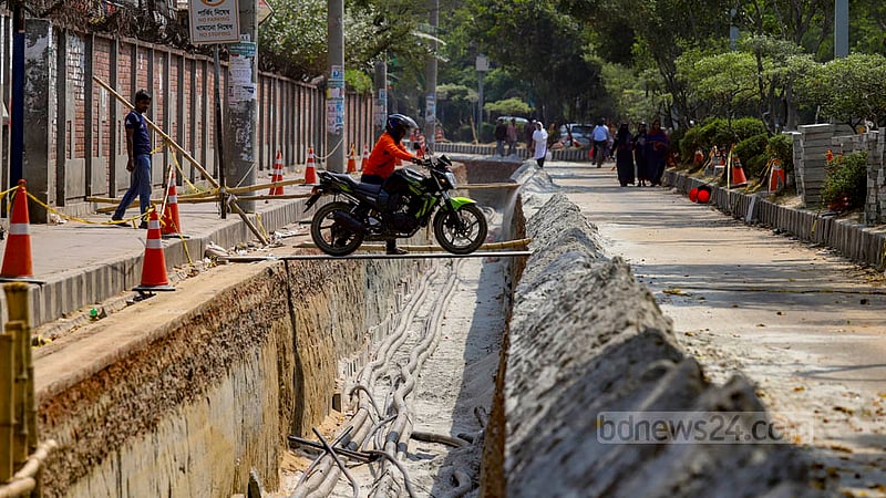 A motorcyclist crosses a hole by using an iron sheet as parts of Hatirjheel Link Road in Dhaka are being dug up for the installation of DPDC cables.