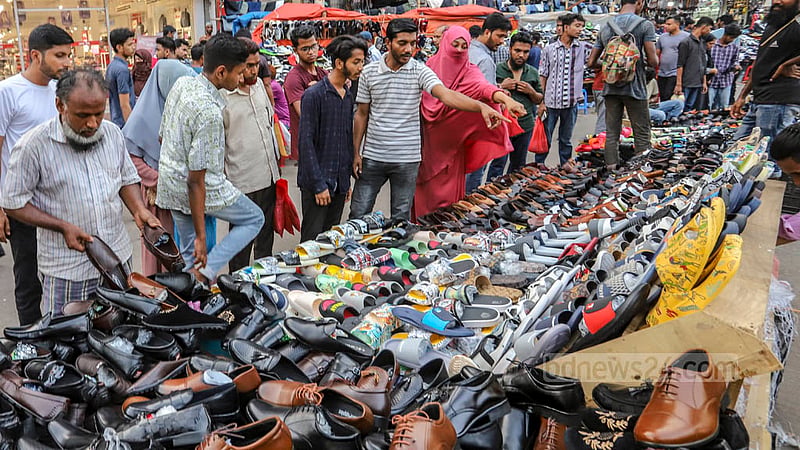A customer checks footwear at a makeshift shop on the footpath in Dhaka before Eid-ul-Fitr.