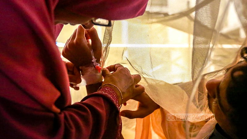 The mother of dengue fever patient Mehedi Hasan fixes his venous cannula at the Mugda Medical College Hospital on Wednesday, May 31, 2023. Photo: Tawhiduzzaman Tapu