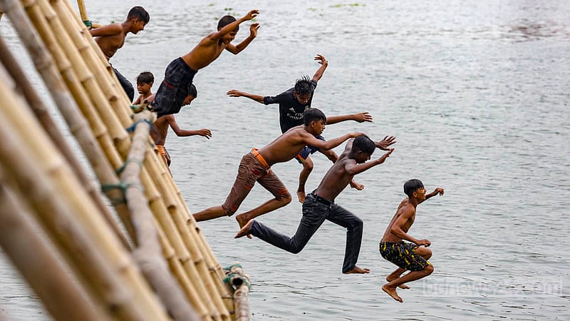 Children leap into the Buriganga River from bamboo structures set up to help load sand onto vessels in the Munshikhola area of Dhaka's Shyampur. Photo: Mahmud Zaman Ovi