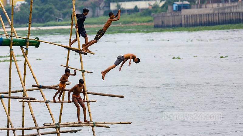 Children jump into the Buriganga River from bamboo structures set up to help load sand onto vessels in the Munshikhola area of Dhaka's Shyampur. Photo: Mahmud Zaman Ovi