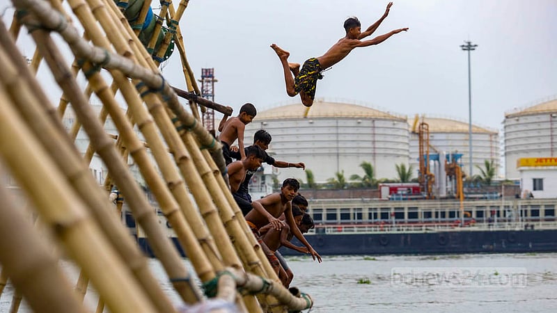 Children jump into the Buriganga River from bamboo structures set up to help load sand onto vessels in the Munshikhola area of Dhaka's Shyampur. Photo: Mahmud Zaman Ovi
