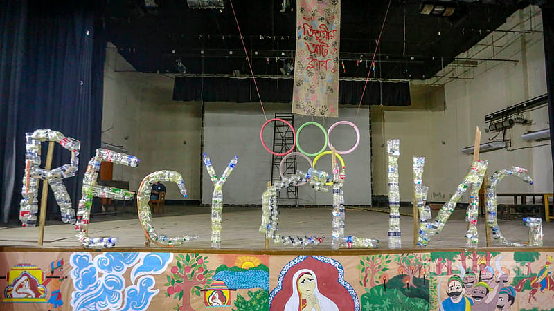 Members of the Titumir Art Club put up a writing that says “Recycling” with unused plastic bottles in an exhibition at the Government Titumir College on Monday, May 29, 2023. Photo: Tawhiduzzaman Tapu