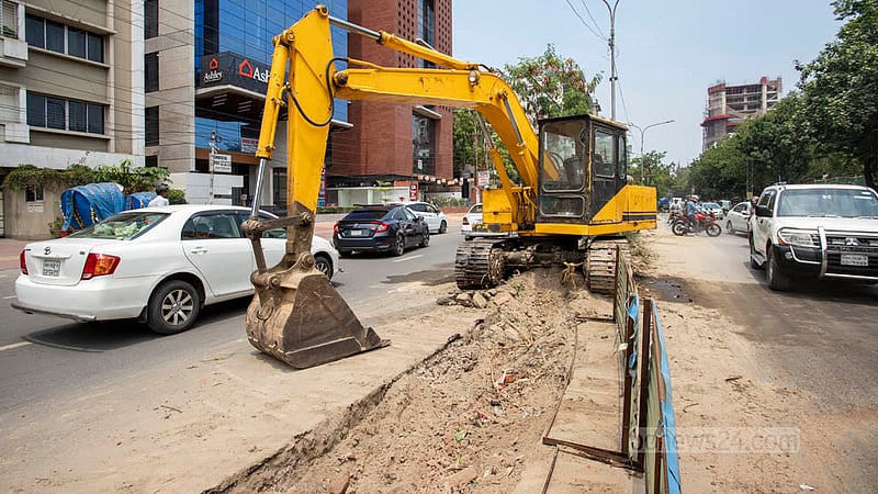 Workers use an excavator to uproot the trunks of felled trees along the old median of Saat Masjid Road. Photo: Asif Mahmud Ove