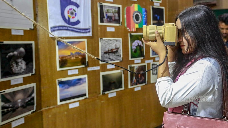 A student looks into a camera made out of papers in an exhibition organised by the Titumir Art Club at the Shaheed Barkat Auditorium on Monday, May 29, 2023. Photo: Tawhiduzzaman Tapu