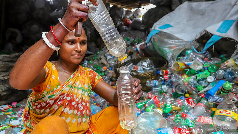 May 7: A woman collects cooking oil from a trashed bottle in Kamrangirchar as prices skyrocket.