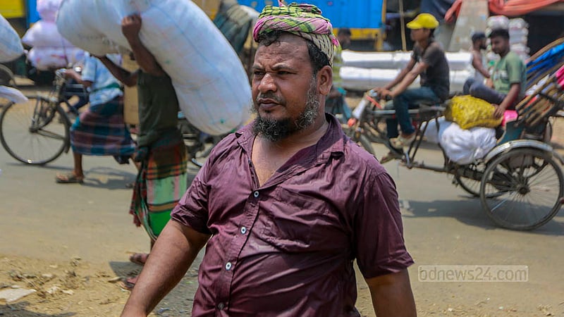 Mohammad Alim Hossain sweated profusely while lifting a sack amidst the scorching afternoon heat in Dhaka's Swarighat area on Tuesday, Jun 6, 2023. Photo: Tawhiduzzaman Tapu